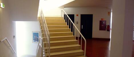 Una escalera con barandillas blancas que conduce a una plataforma. En la plataforma hay puertas, una de ellas con un letrero que indica 'SI'.