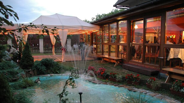 Un giardino con una fontana, una tenda e un edificio con ampie finestre.