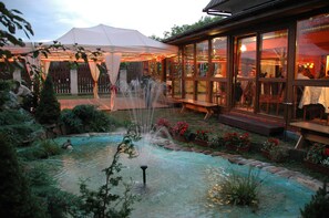 A garden with a fountain, a tent, and a building with large windows. - Hotel Bona (Kraków)