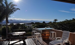 A deck with a wooden table, chairs, and a barrel labeled "Tevenwacht". - Amakaya Backpackers Travelers Accommodation (Plettenberg Bay)