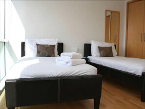 A hotel room with two single beds, a large window, and a wardrobe. - Glasgow Lofts (Glasgow)
