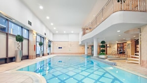 An indoor swimming pool with a tiled floor, surrounded by columns and potted plants. - Glasgow Lofts (Glasgow)