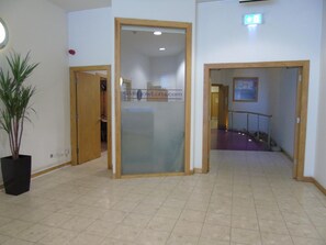 A hallway with a glass partition, a potted plant, and a staircase leading to an upper floor. - Glasgow Lofts (Glasgow)