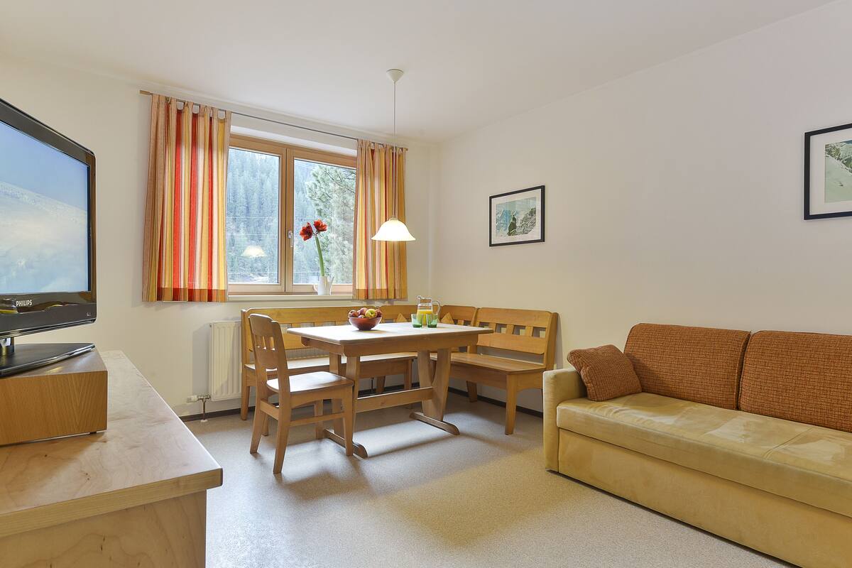 A cozy living room with a wooden table, a sofa, and a television.