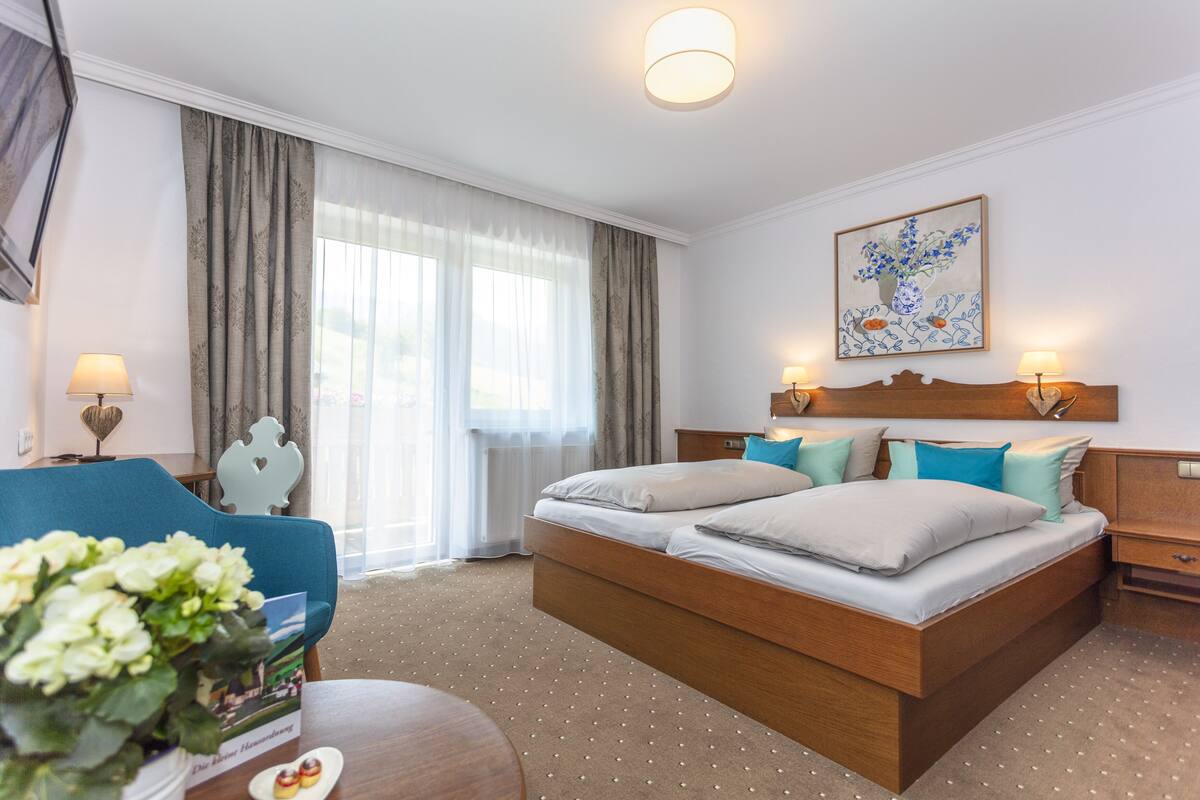 Habitación de hotel con una cama grande, un escritorio, una silla y una ventana con cortinas.