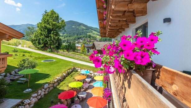 Een balkon met een stenen muur, houten balken en kleurrijke parasols.