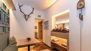 Een modern interieur met houten meubilair, een opgehangen herten schedel en een open haard met boeken.