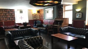 A library with leather sofas, wooden tables, and bookshelves. - New Union Hotel (Manchester)