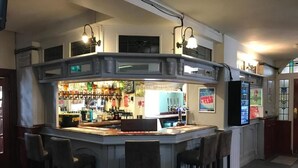 A bar area with a counter, stools, and a variety of bottles and glasses. - New Union Hotel (Manchester)