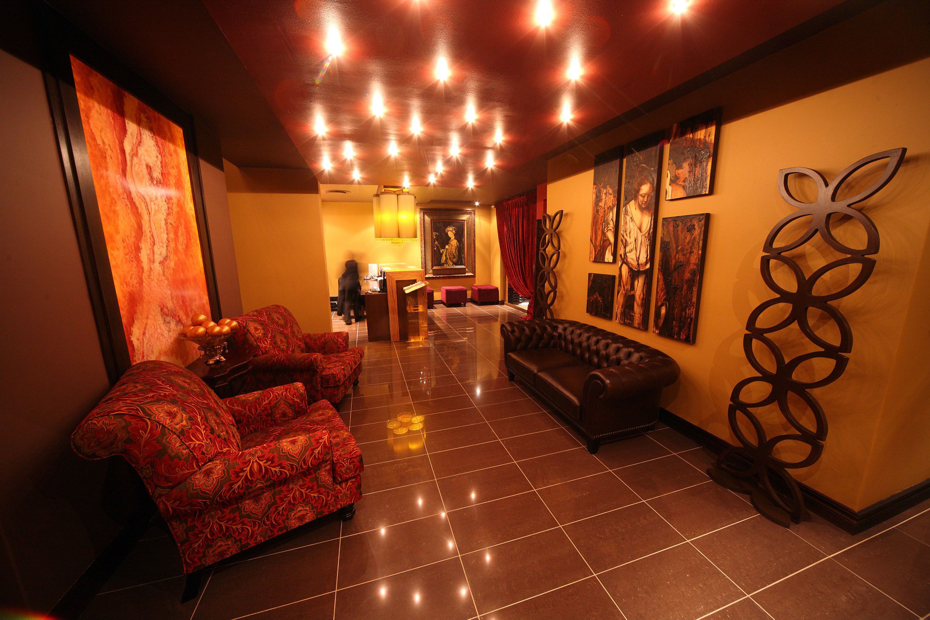 A lobby with a red patterned sofa, a leather couch, and a decorative metal sculpture.
