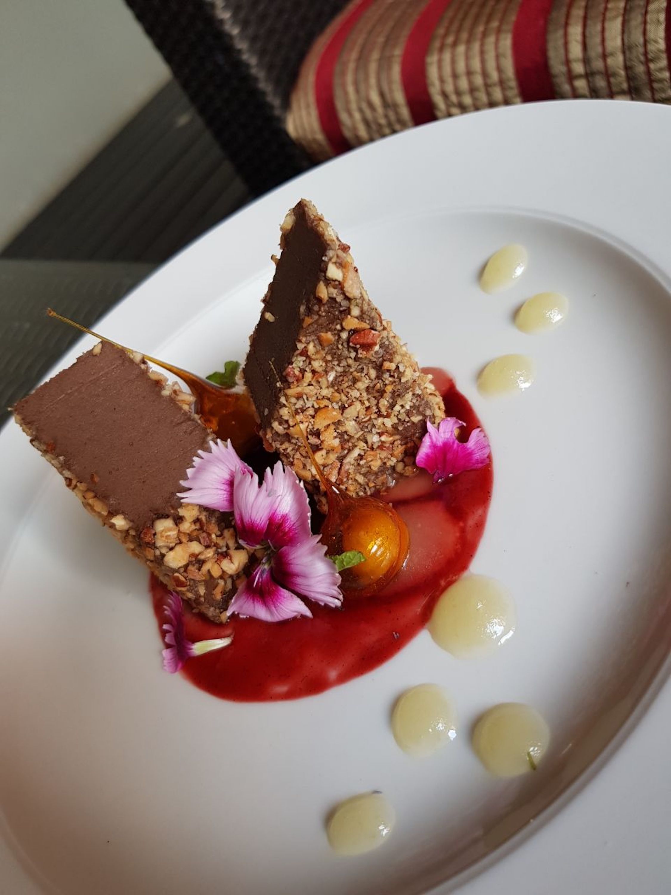 A dessert with nuts and chocolate on a white plate.