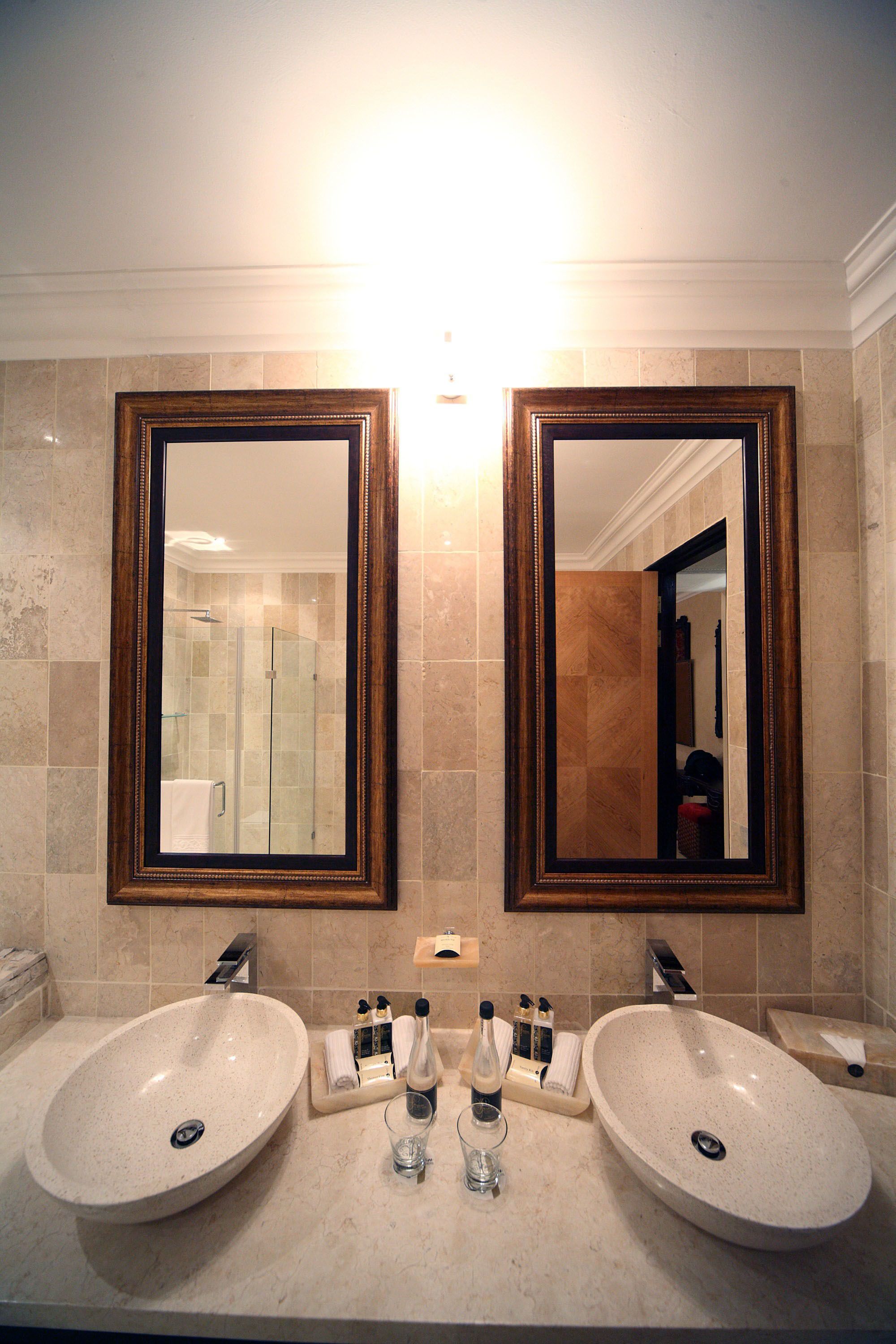 A bathroom with two sinks, a mirror, and a shower.