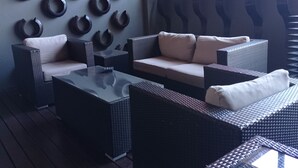 A modern outdoor seating area with wicker furniture and a glass-top table.