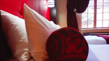 A bed with white bedding and a red and black patterned pillow.