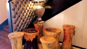 A staircase with a tufted leather wall, a floor lamp, and wooden stools.