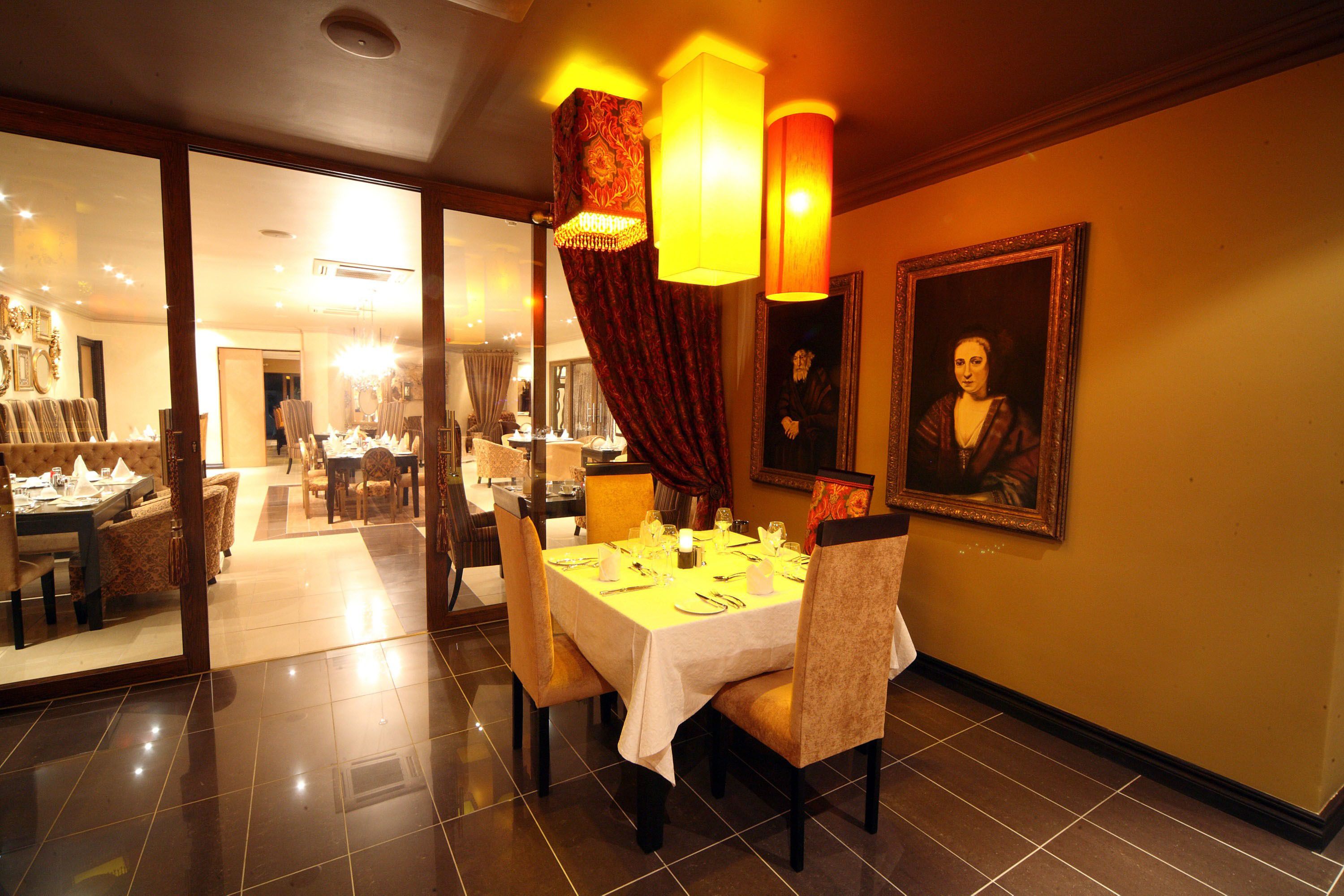 Uma sala de jantar com uma mesa posta para quatro pessoas, cadeiras e um quadro na parede.