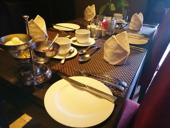 A dining table set with plates, bowls, cutlery, and glasses, indicating a meal setting.