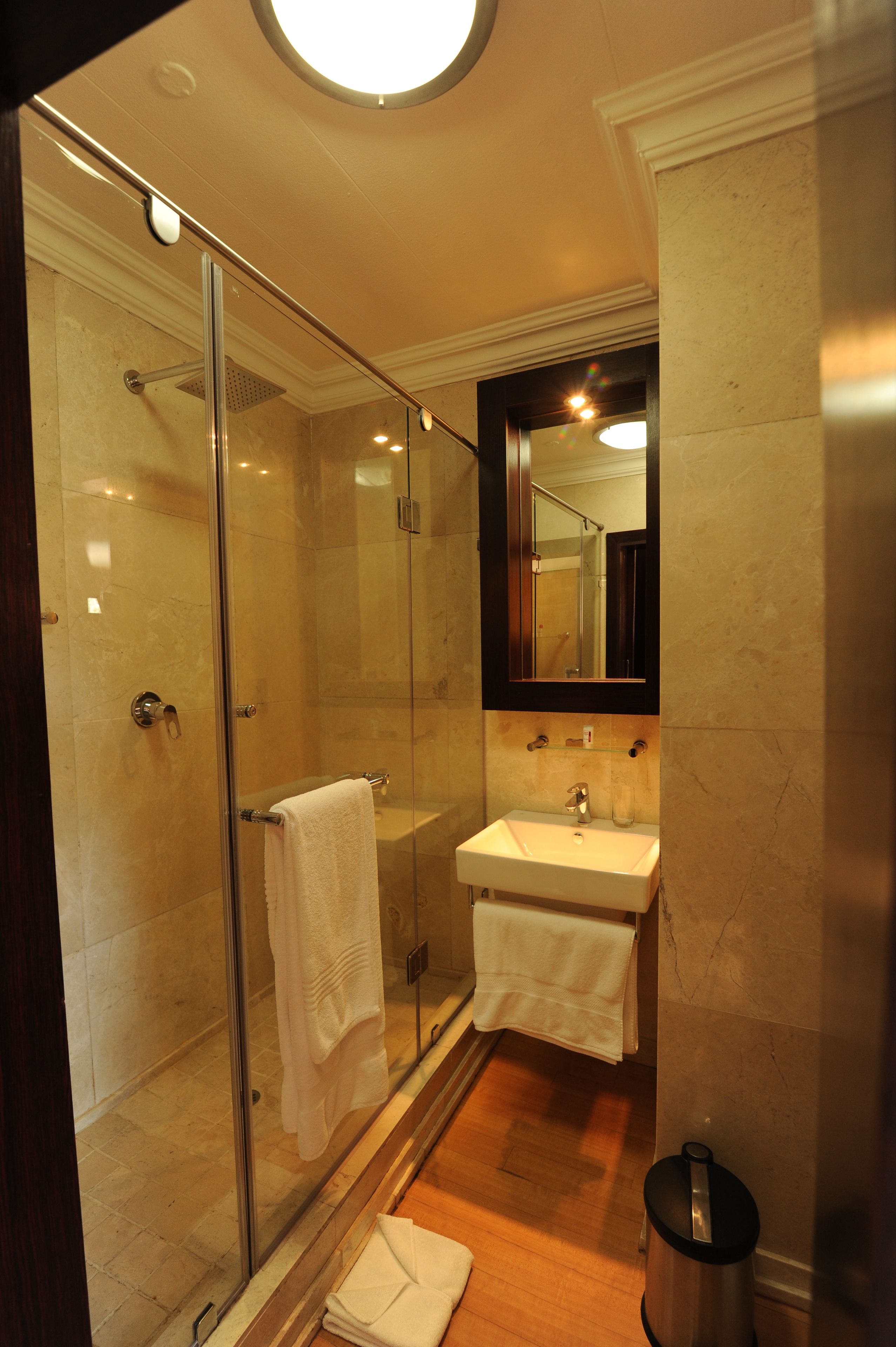 Un bagno moderno con doccia a schermo, lavandino bianco e un ampio specchio.
