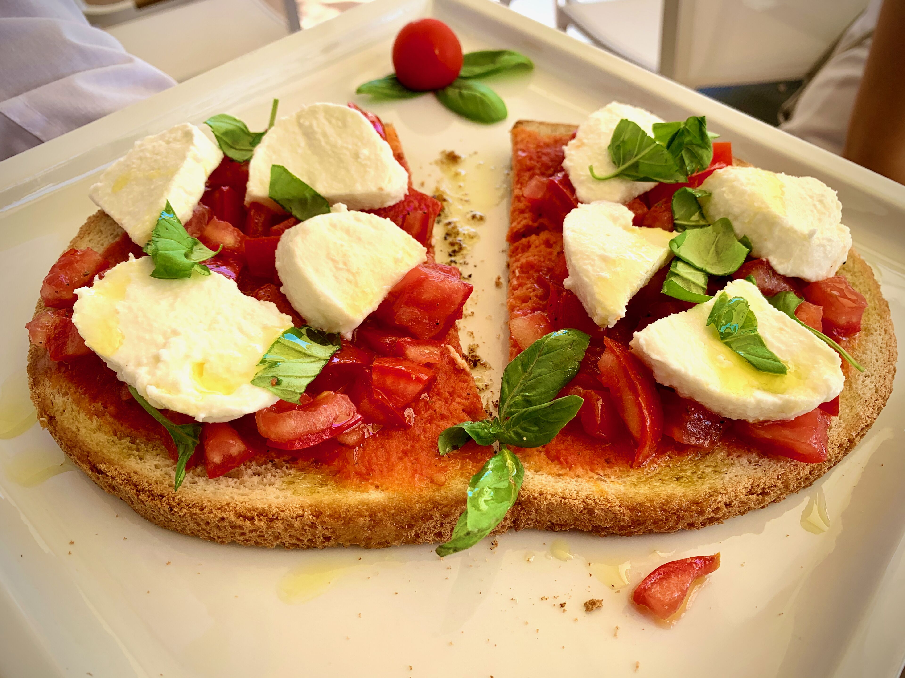 A dish with bread, tomatoes, cheese, and basil.