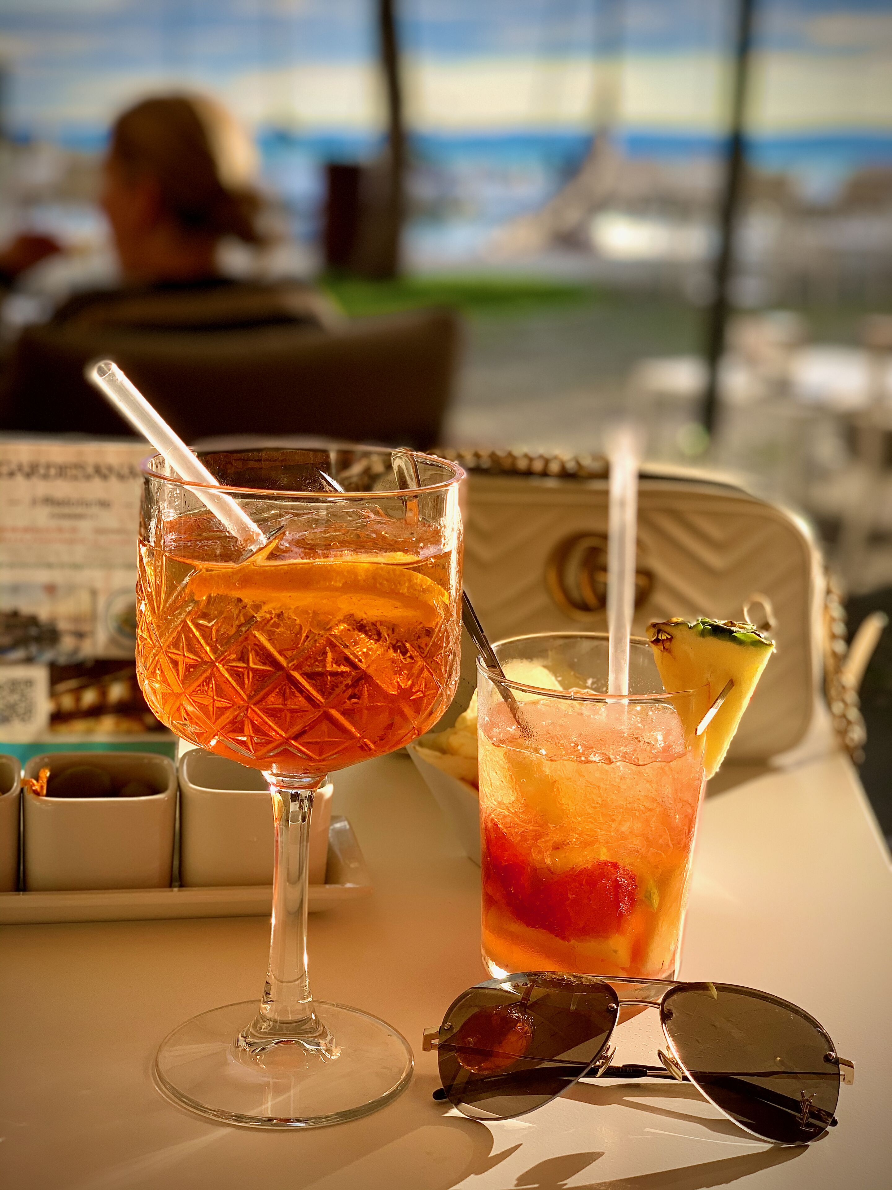 Two cocktails on a table with a menu and sunglasses.