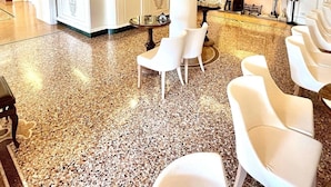 A lobby with a bar area, white chairs, and a decorative ceiling. - Albergo Gardesana (Torri del Benaco)