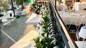 A terrace with outdoor seating, a view of the sea, and a pergola with climbing plants. - Albergo Gardesana (Torri del Benaco)
