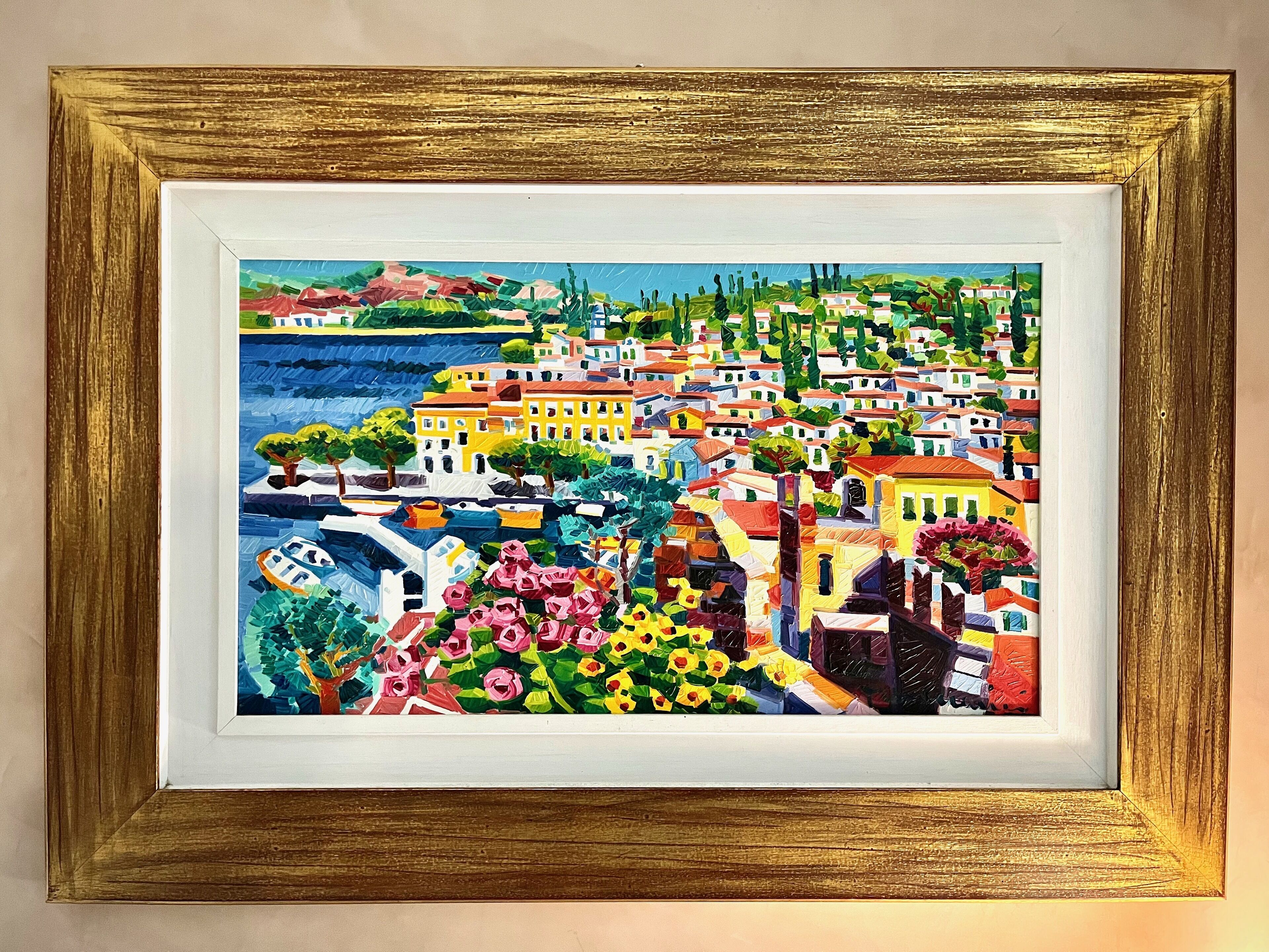 Pintura emoldurada de uma vila costeira colorida, com edifícios, barcos e vegetação.
