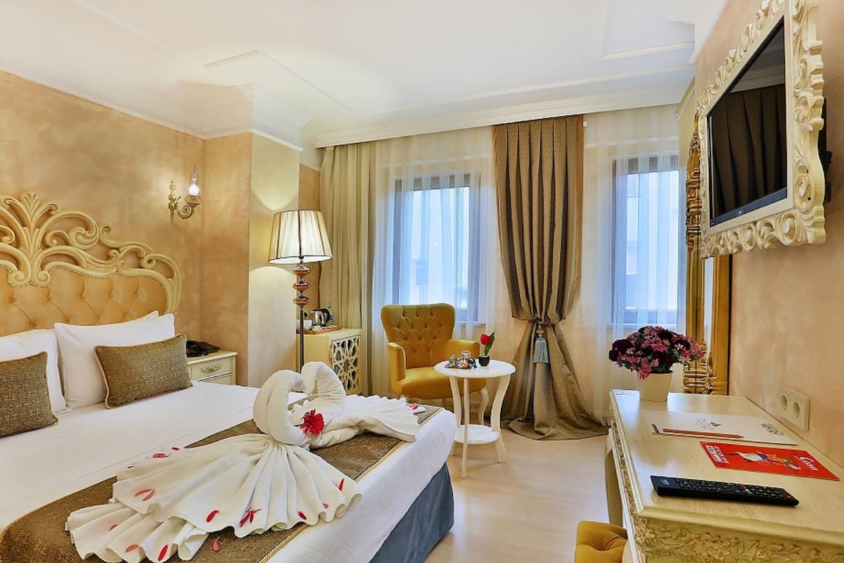 A hotel room with a large bed, a desk, a chair, and a TV.