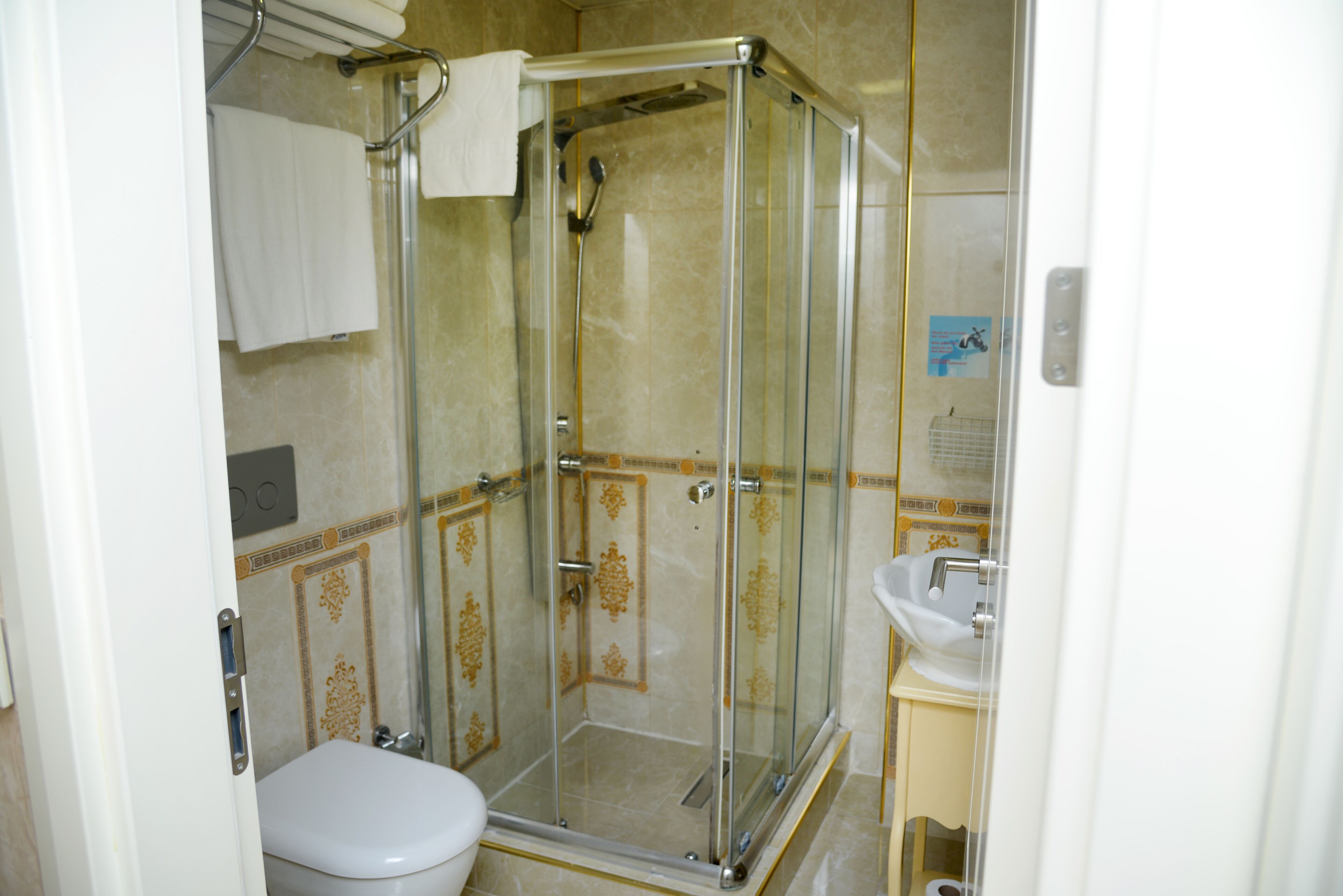Un baño con ducha de mampara de vidrio, inodoro y lavamanos.
