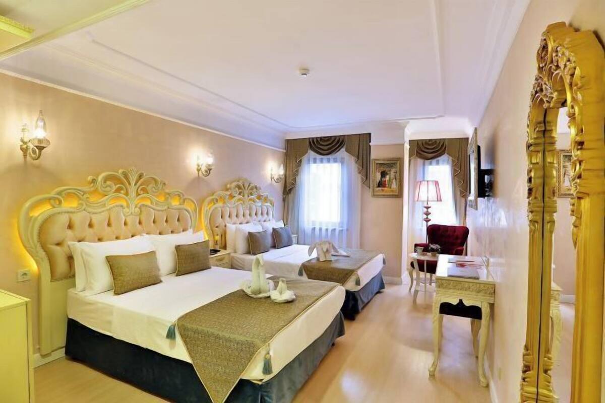 A hotel room with two beds, a desk, a chair, and a large mirror.