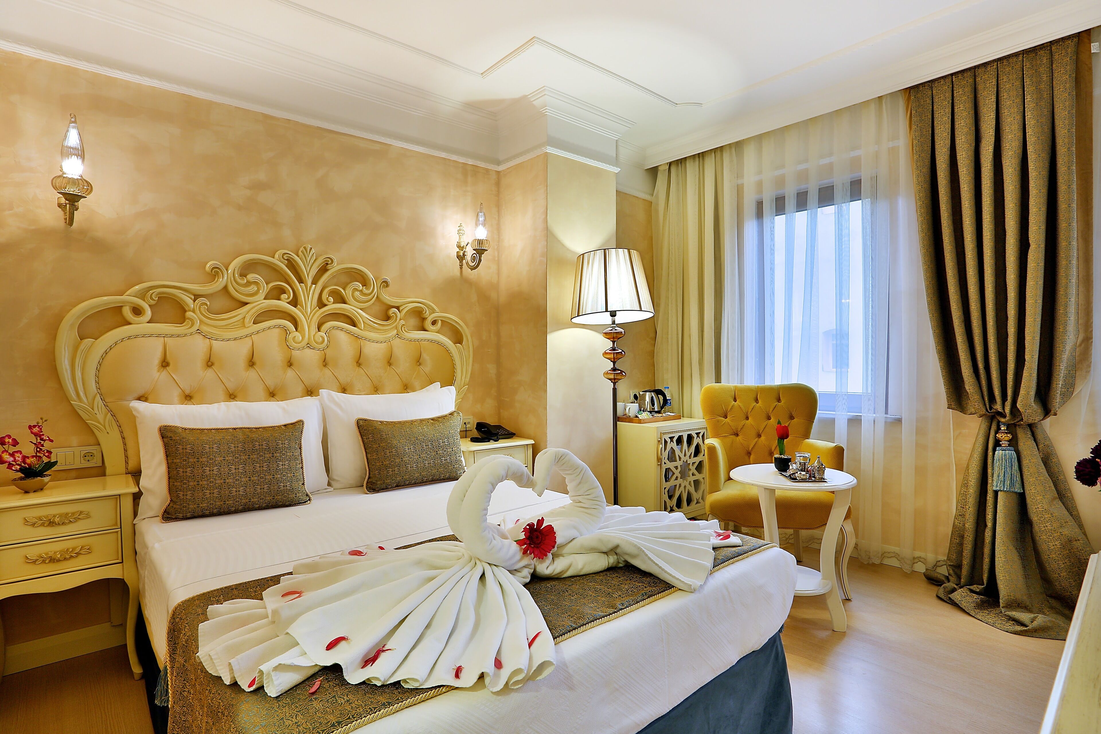 A hotel room with a large bed, a chair, a small table, and a lamp.