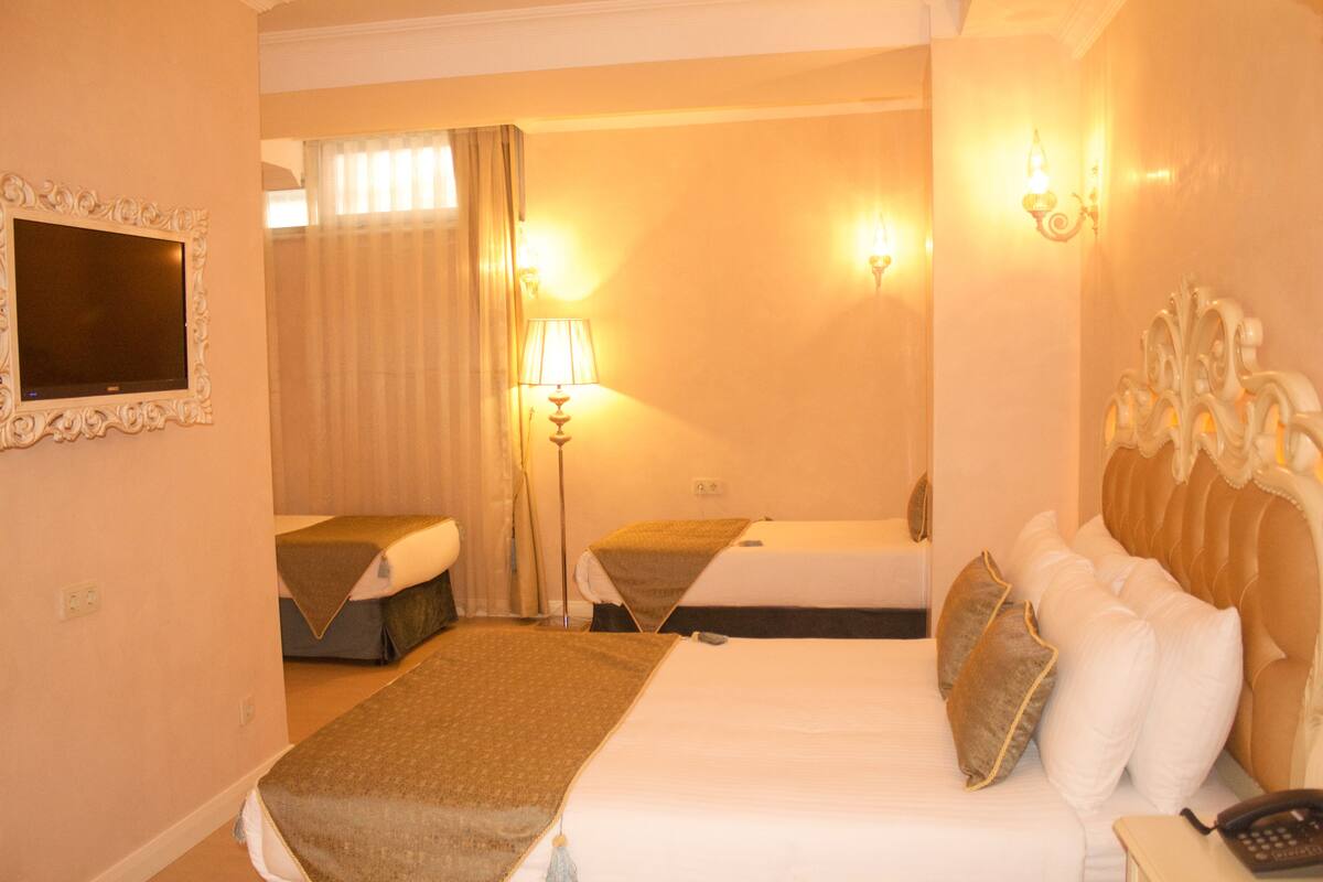 A hotel room with two beds, a flat-screen TV, a lamp, and a telephone.