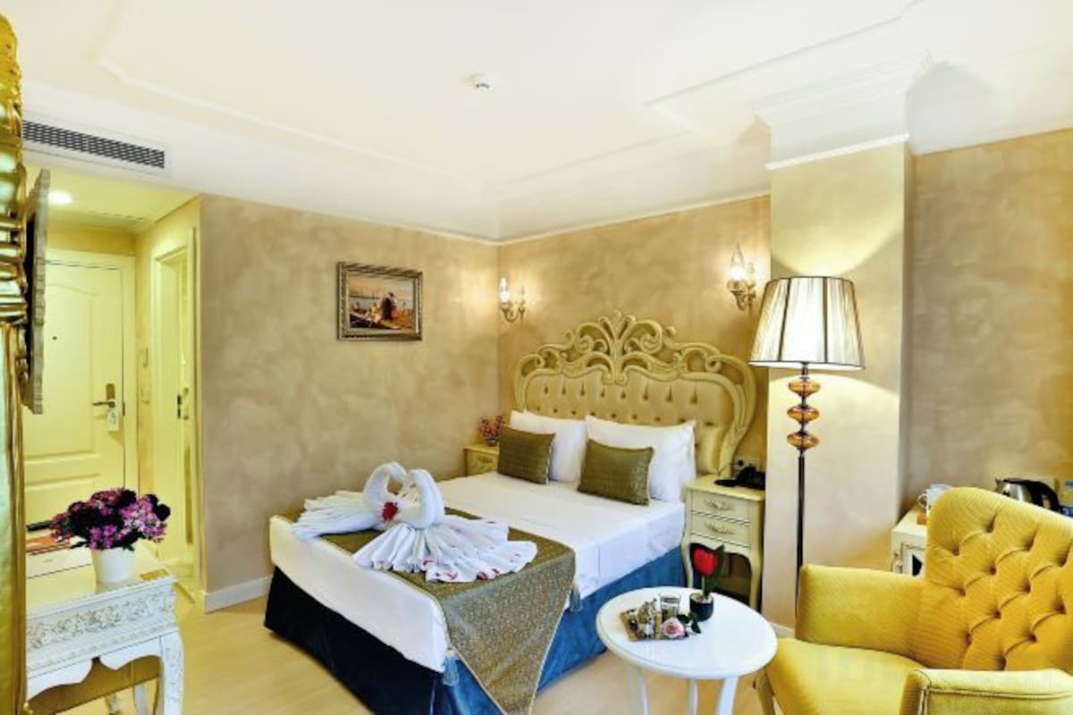 A hotel room with a large bed, bedside tables, a lamp, a chair, and a small table.