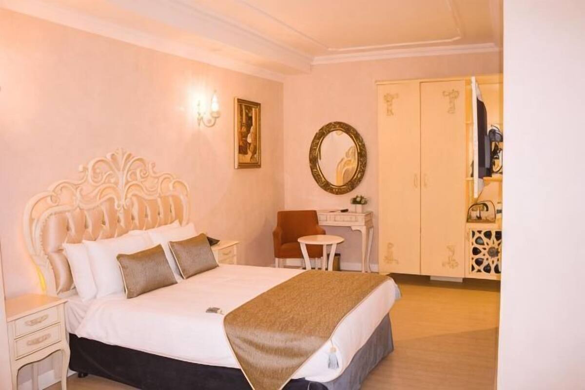 A bedroom with a white bed, a desk, a chair, and a wardrobe.