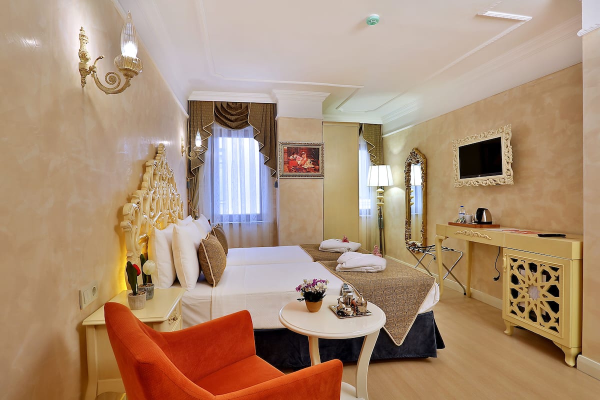 A hotel room with a bed, a desk, a chair, a television, and a bathroom mirror.