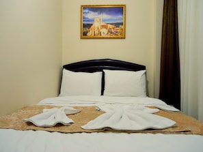 Una habitación de hotel con cama, almohadas, una colcha y un cuadro en la pared.