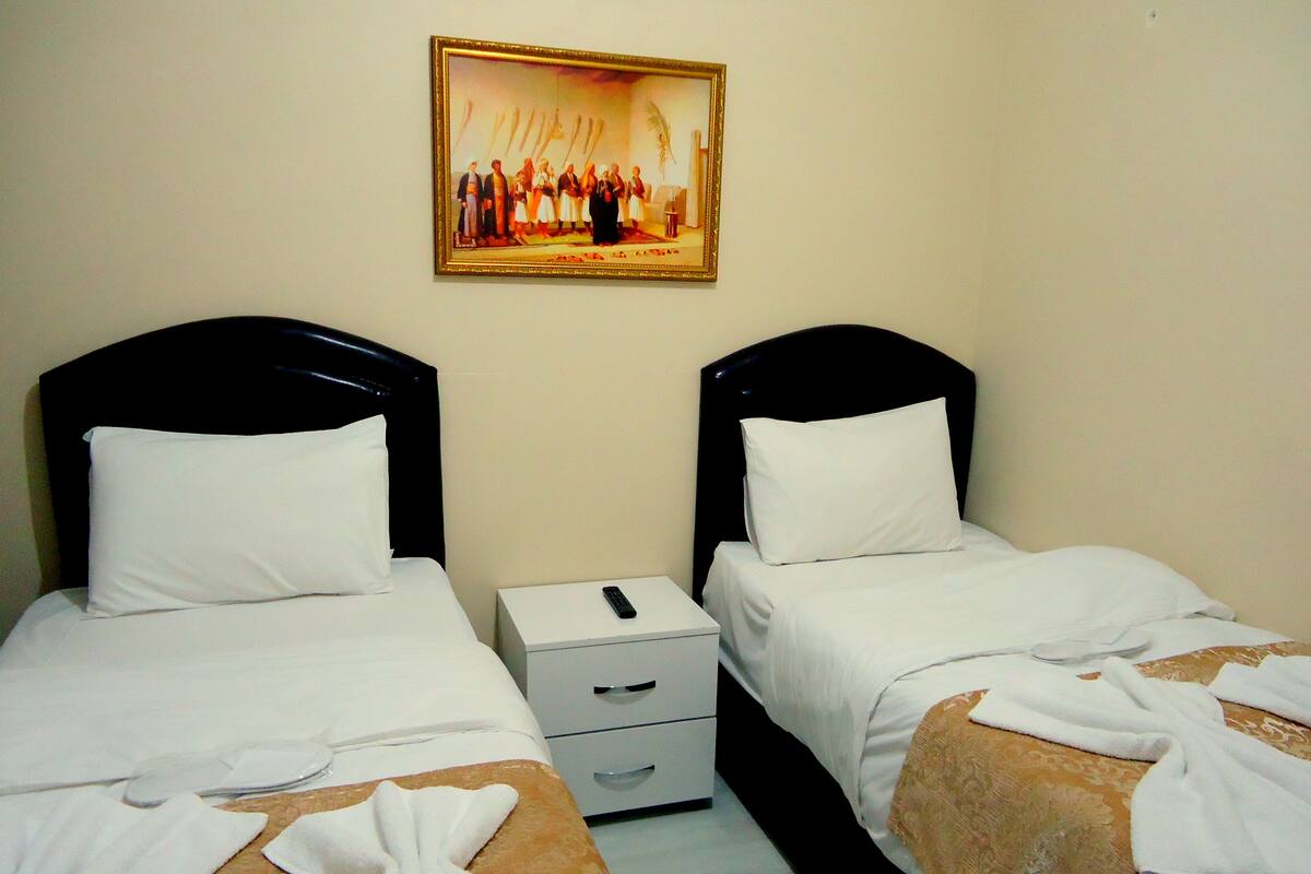 Una habitación de hotel con dos camas, una mesita de noche y un cuadro en la pared.
