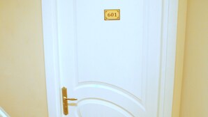 A white door with a number plate, a red carpeted staircase, and a fire extinguisher. - Tolga Hotel (Istanbul)