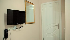 A room with a television mounted on the wall, a telephone, and a door with a simple design. - Tolga Hotel (Istanbul)