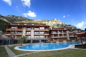 Una piscina al aire libre, sombrillas, sillones reclinables de piscina