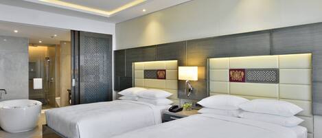 A hotel room with two beds, a bathtub, and a shower area.