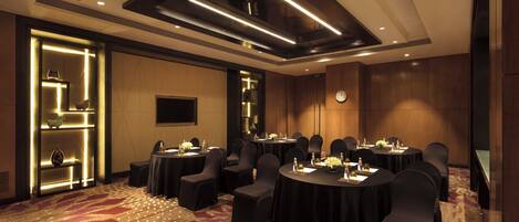 A conference room with round tables, black chairs, and a patterned carpet.