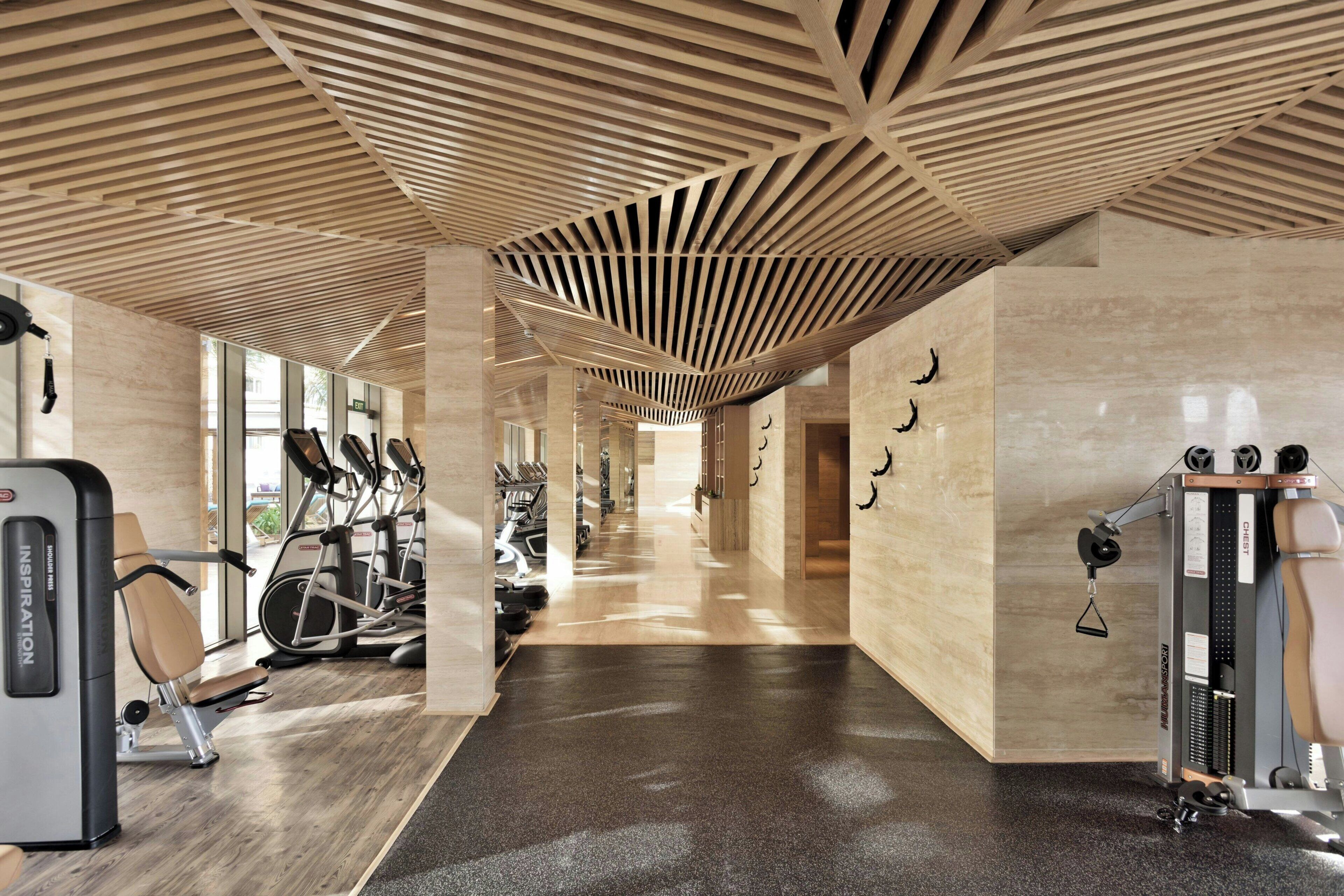 Ein Fitnessraum mit Trainingsgeräten, einer Holzbalkendecke und einem Flur.