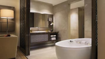 Un baño moderno con una bañera grande, un tocador con espejo y una lámpara de pie.