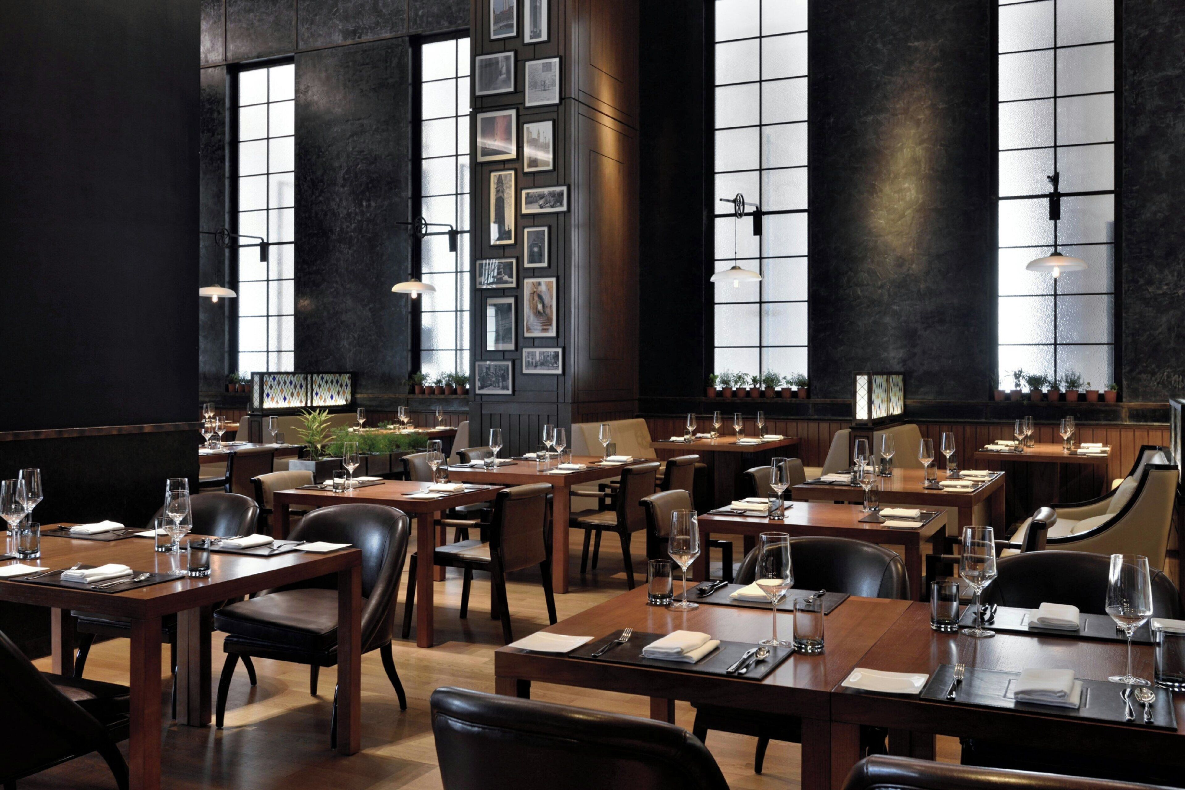 Een restaurant met meerdere eettafels, stoelen en hangende吊り下げ灯.