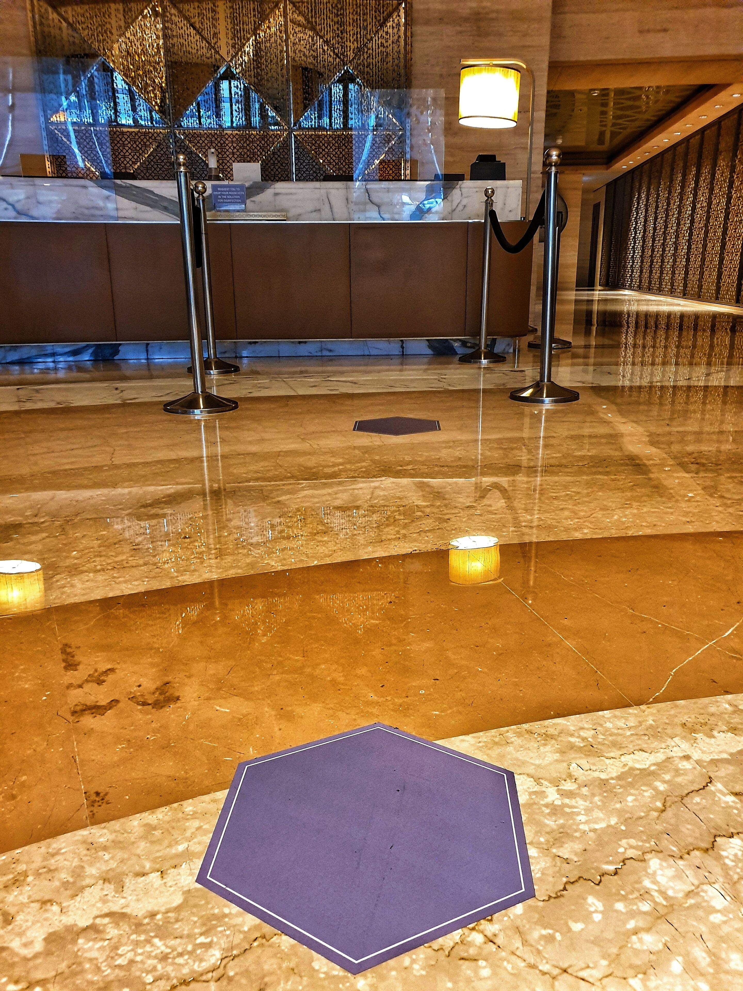 A lobby area with a marble floor, a reception desk, and a decorative wall with a geometric pattern.