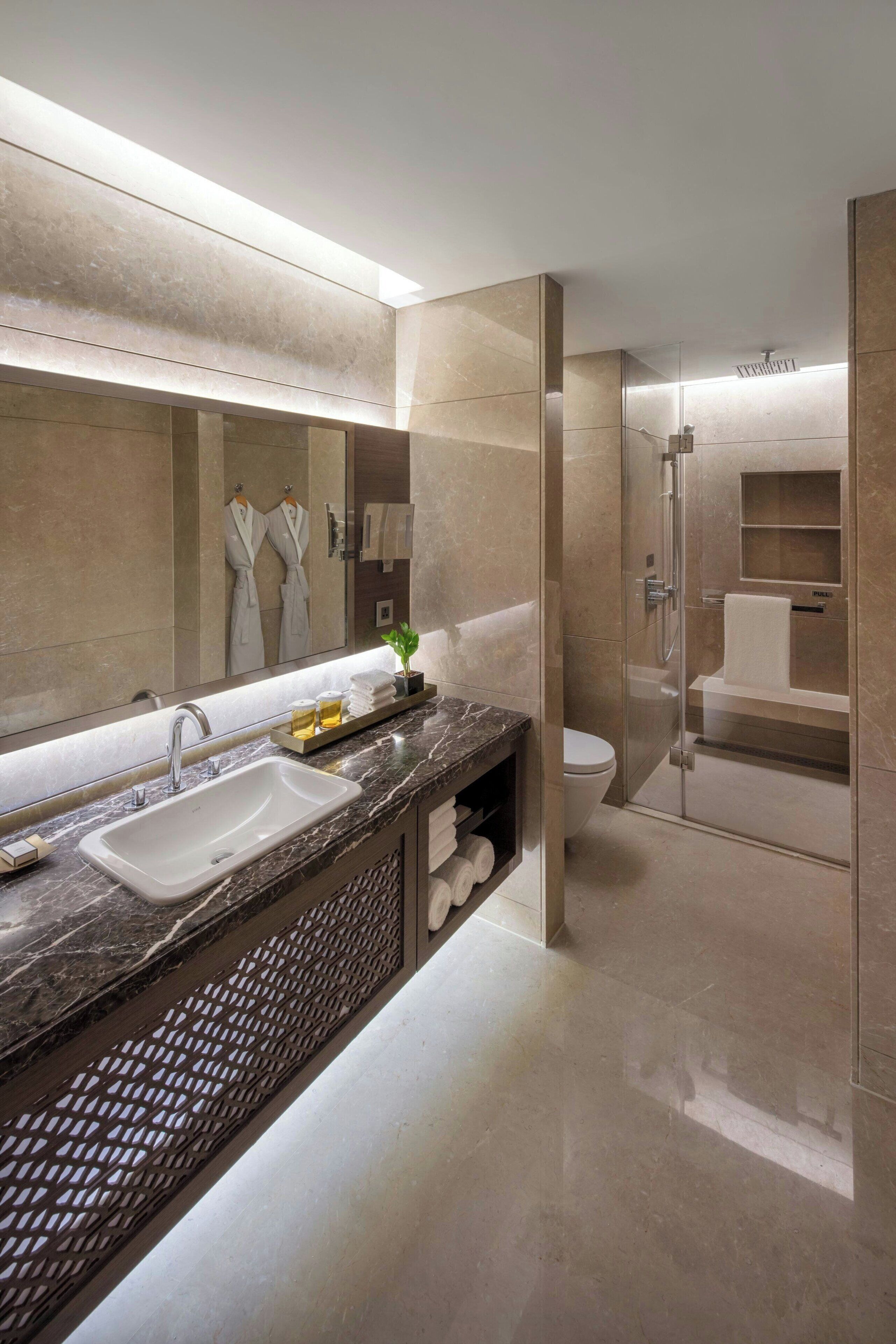 Une salle de bain moderne avec un grand miroir, un lavabo et un espace douche.