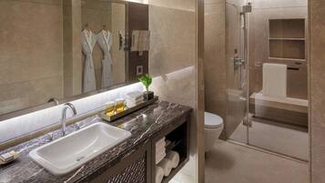 Une salle de bain moderne avec un grand miroir, un lavabo et un espace douche.
