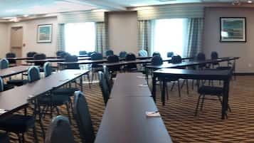 A conference room with multiple tables and chairs, a patterned carpet, and framed pictures on the walls.