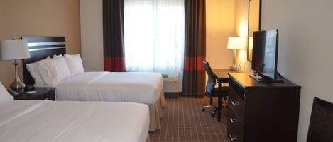 Quarto de hotel com duas camas, uma mesa, uma cadeira, televisão e uma janela grande com cortinas.